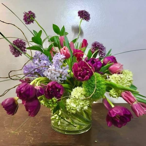 Purple and pink tulips with allium and hydrangea in a glass vase