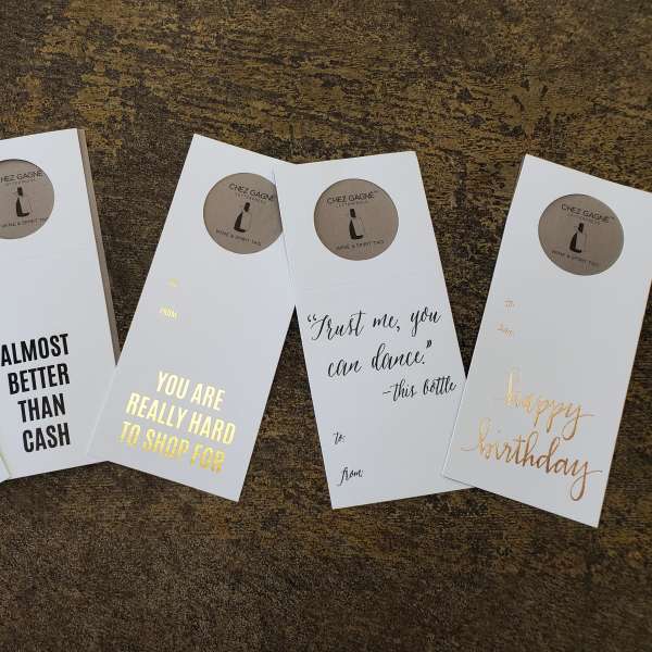 Five greeting card sleeves with gold and black text on a textured surface.