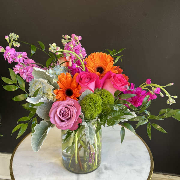 Mixed bouquet in a clear glass vase with pink roses and orange gerbera daisies