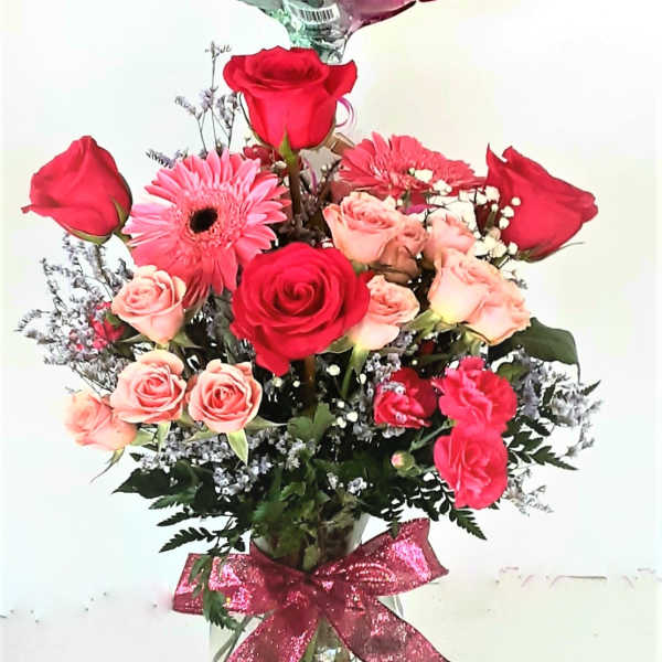 Birthday balloon above a rose bouquet in a glass vase