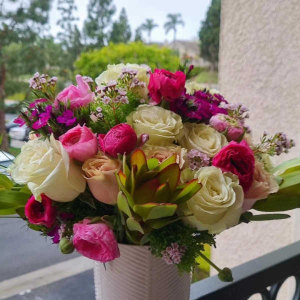 Pink and white rose bouquet in a white vase with a succulent accent