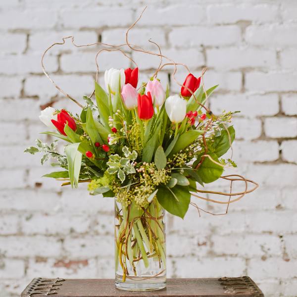 Bouquet of red, white, and pink tulips in a clear glass vase