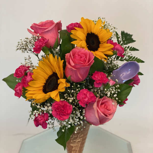 Bouquet of pink roses, sunflowers, and carnations in a vase