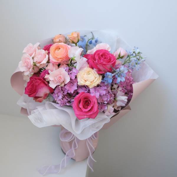 Bouquet of pink and peach roses with pastel filler flowers in wrapping paper