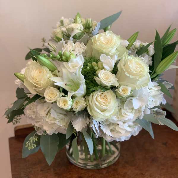 White roses and lilies arranged in a glass vase