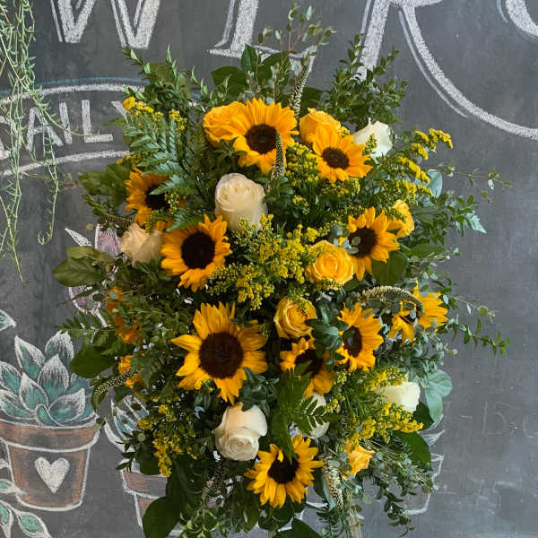 Large floral arrangement with sunflowers and white roses on an easel
