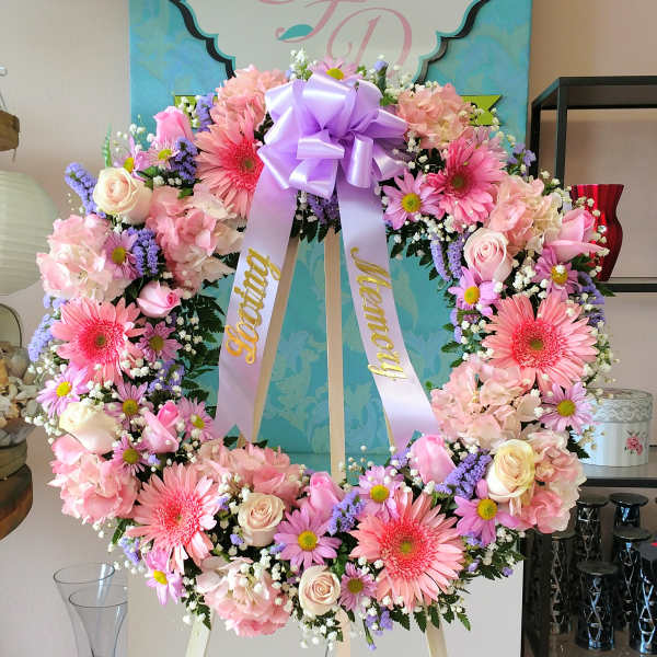 Large pink and lavender floral wreath with a purple bow on an easel