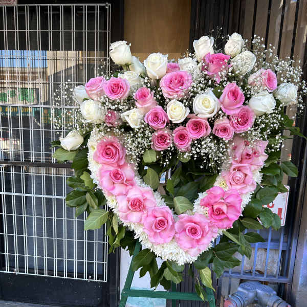 Heart-shaped pink and white rose standing spray on an easel