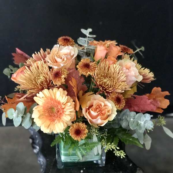 Peach and orange bouquet in a square glass vase