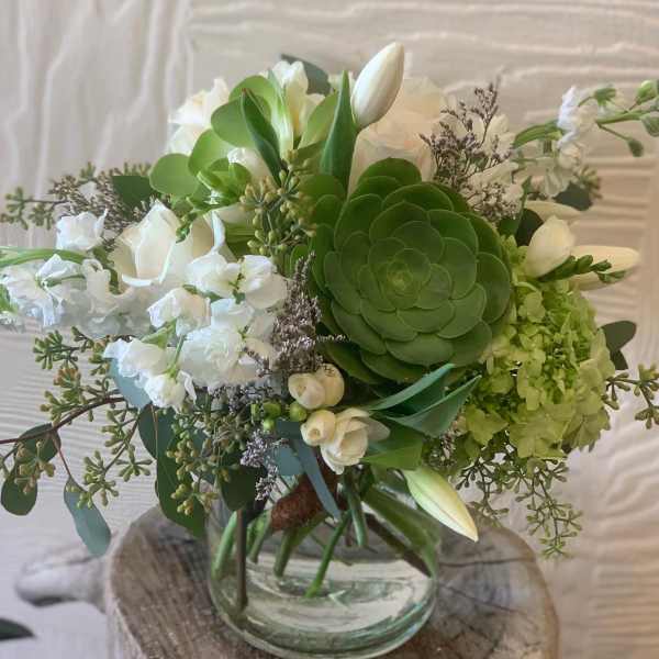 White and green floral bouquet in a clear glass vase