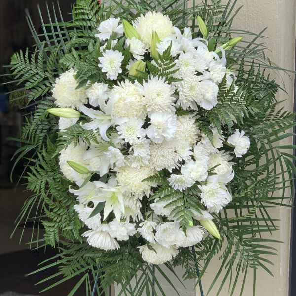 White funeral spray with lilies and chrysanthemums on a stand
