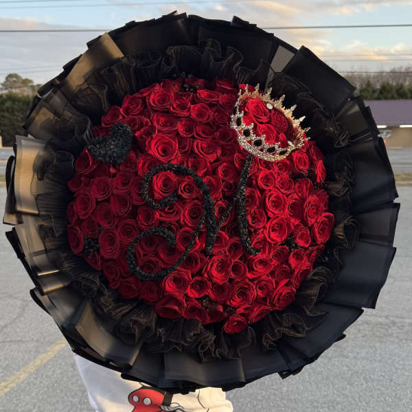 Large bouquet of red roses wrapped in black paper with a crown decoration