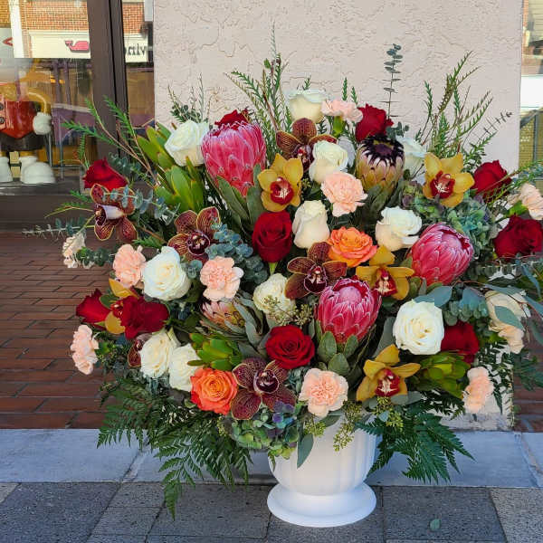 Large mixed floral arrangement in a white pedestal vase