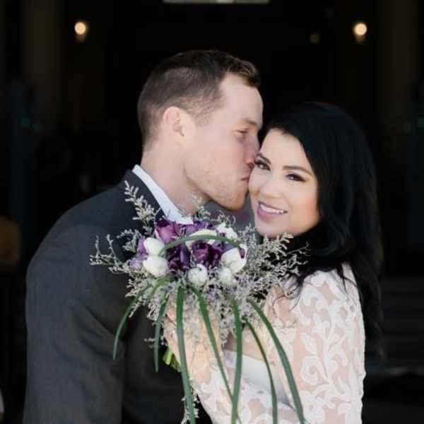 Bride and groom holding a purple and white bouquet