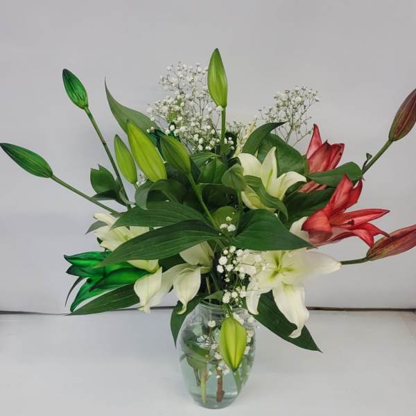 Bouquet of white and red lilies in a clear glass vase