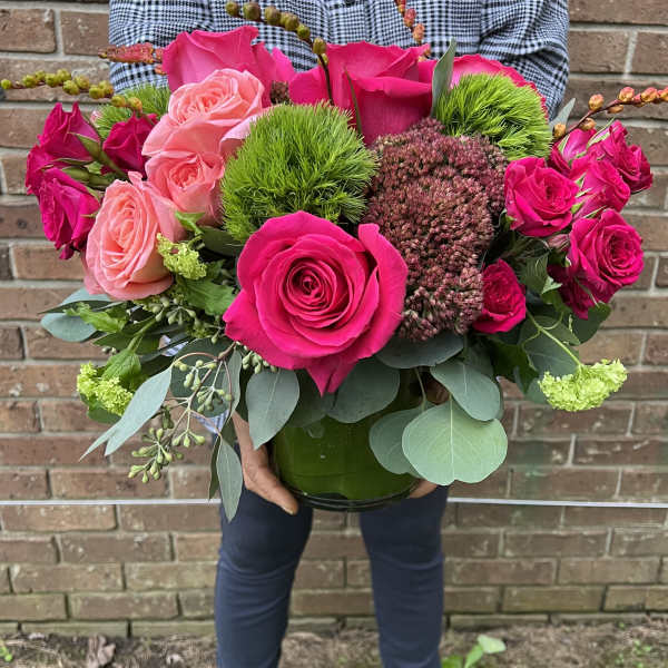 Bouquet of hot pink and blush roses in a green glass vase