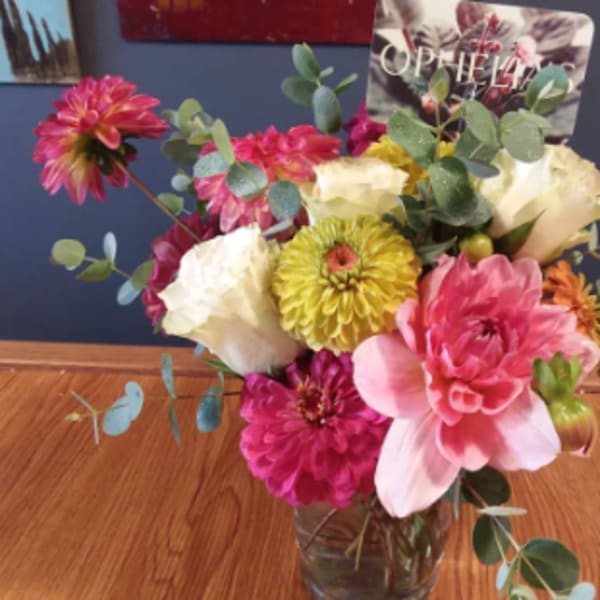 Mixed pink, white, and yellow flowers in a clear glass vase