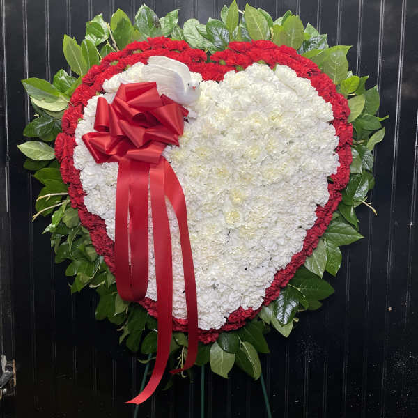 Heart-shaped floral wreath with white and red flowers and a red ribbon bow