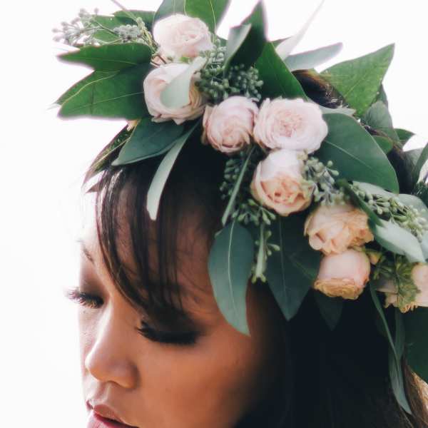 Woman wearing a floral crown of pale pink roses and greenery