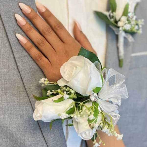 White rose corsage on a gray suit jacket with a matching boutonniere