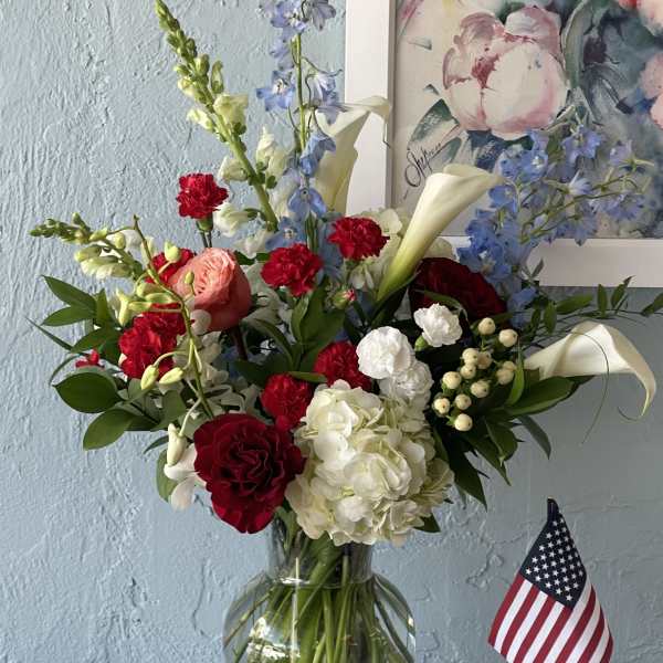 Mixed bouquet in a glass vase with red, white, and blue flowers