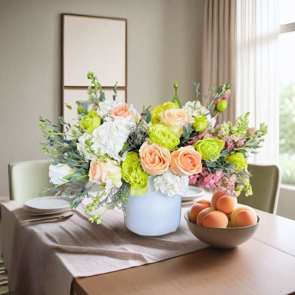 Bouquet of peach and white flowers in a white vase on a dining table