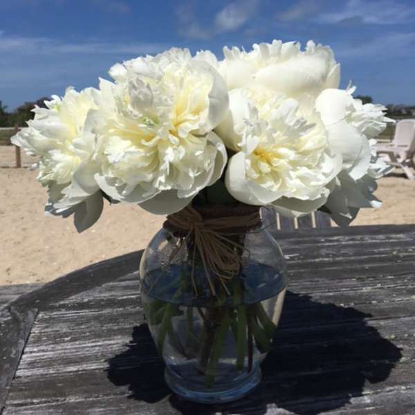 White peony bouquet in a clear glass vase on a table