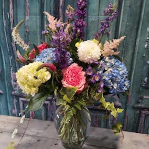 Colorful mixed bouquet in a glass vase with tall purple blooms
