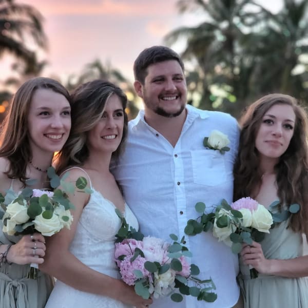 Wedding party holding white and pink bouquets at sunset