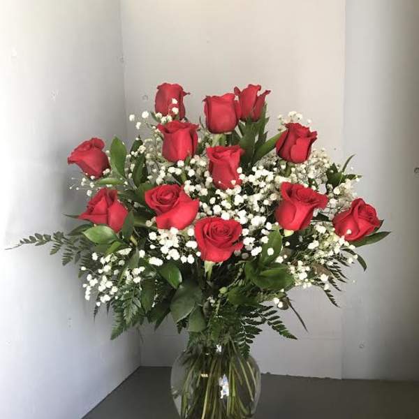 Red roses arranged in a clear glass vase with white baby's breath