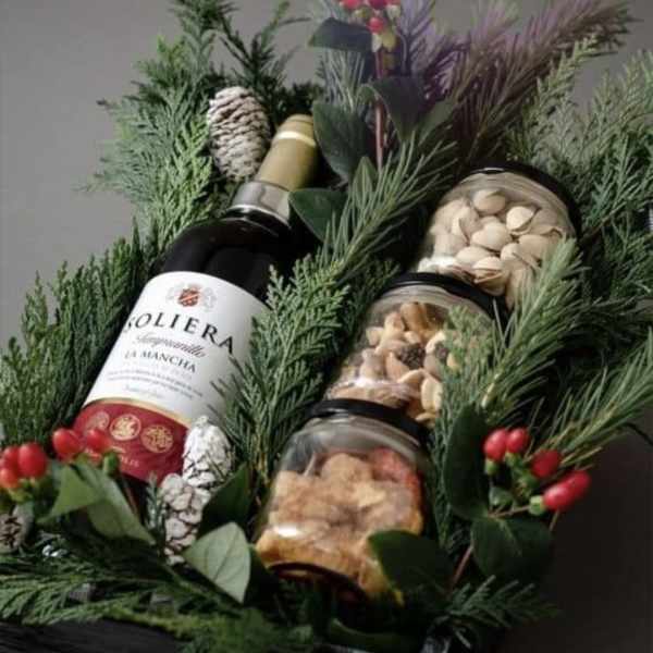 Gift basket with wine, jars of nuts, and evergreen sprigs