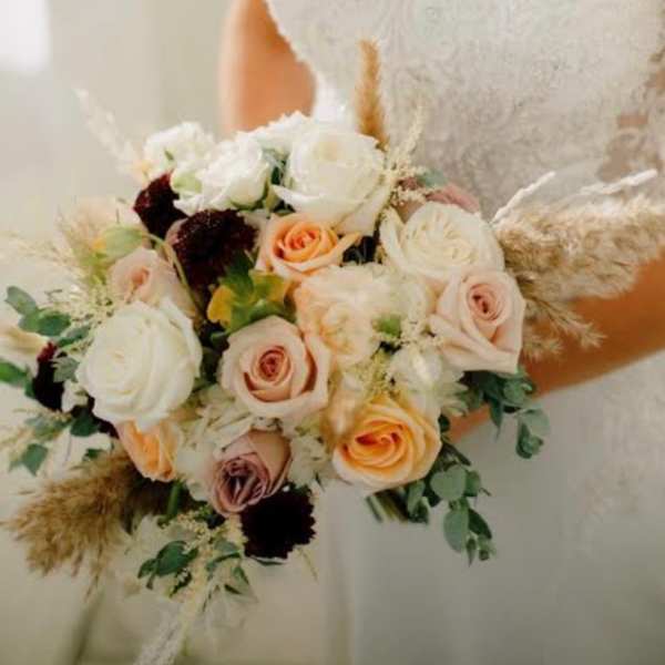 Bride holding a bouquet of white and peach roses