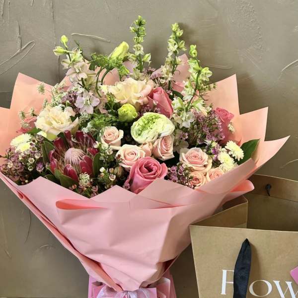 Pink and cream mixed bouquet wrapped in pink paper with a ribbon