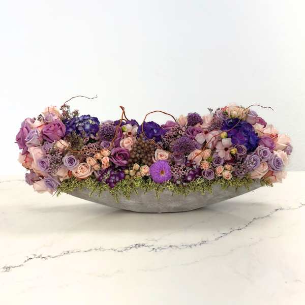 Low floral centerpiece with purple and pink roses in a gray bowl
