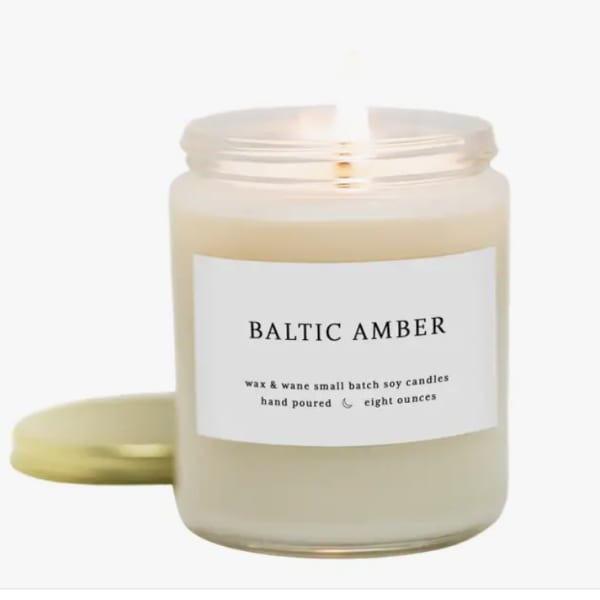 A scented candle in a glass jar with a gold lid