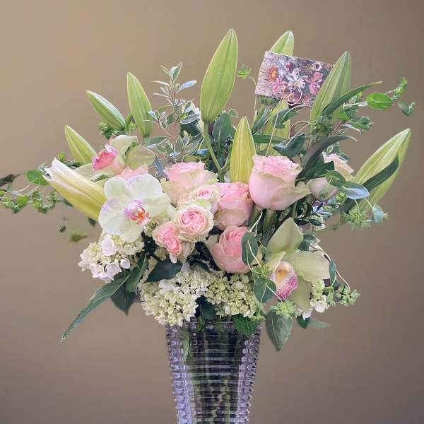 Pink roses and white lilies arranged in a clear glass vase