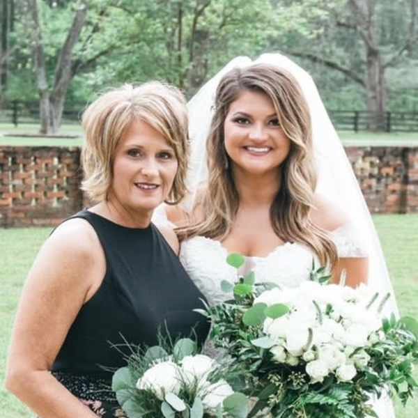 Bride and woman holding white wedding bouquets outdoors