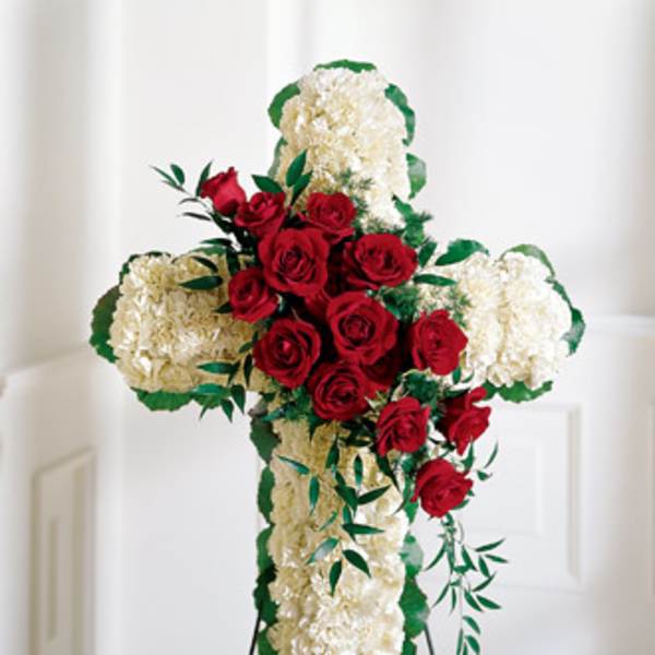 Cross-shaped floral tribute with red roses and white carnations on an easel