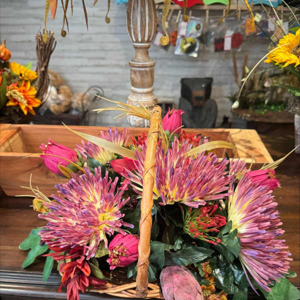 Basket of pink and purple flowers with a woven handle