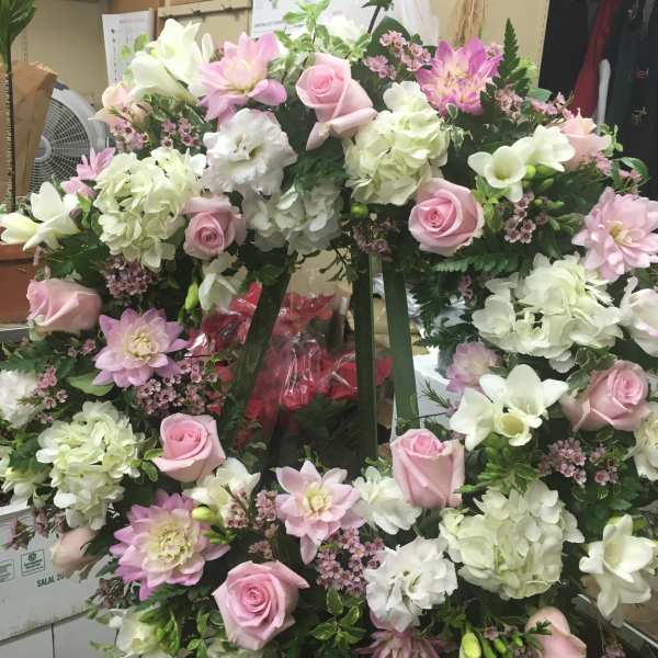 Large pink and white floral wreath on a stand
