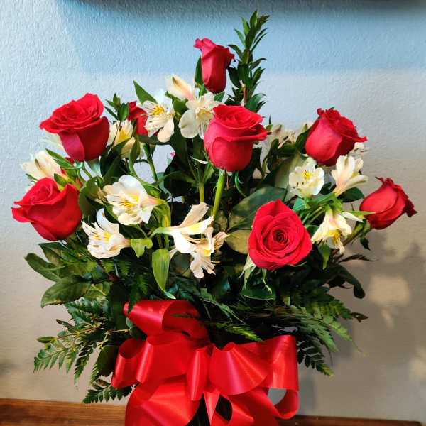 Bouquet of red roses and white alstroemeria in a glass vase with a red ribbon