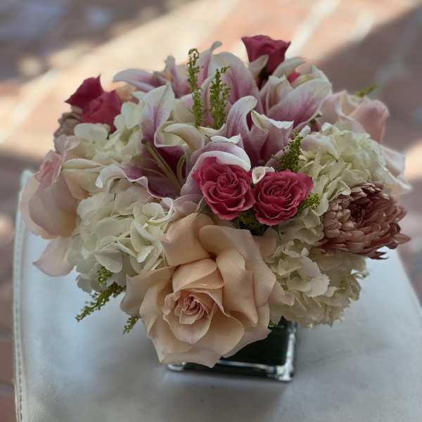 Pink and white bouquet with roses, lilies, and hydrangeas in a square vase