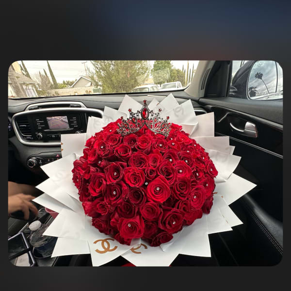 Large bouquet of red roses with a jeweled crown topper and white wrap