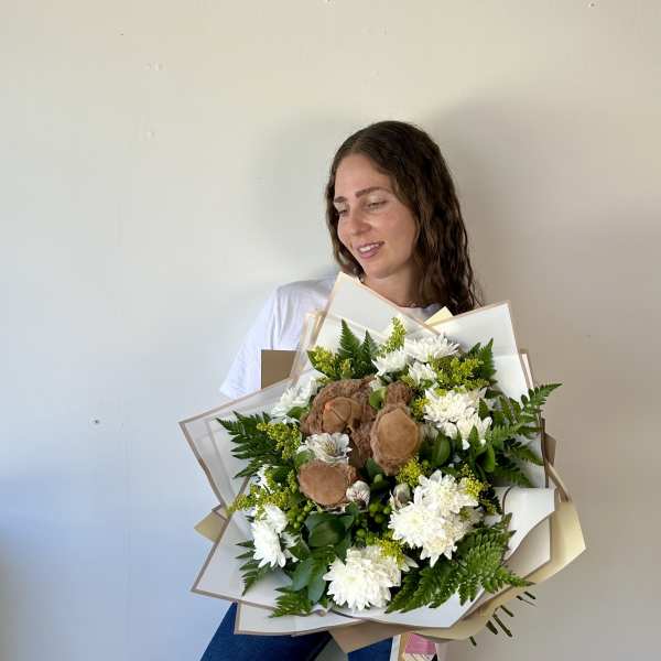 Woman holding a large bouquet of white flowers with brown teddy bears