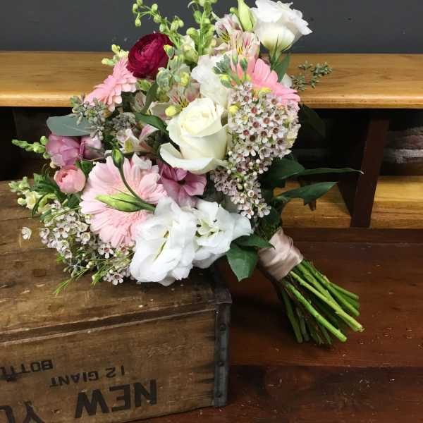 Hand-tied bouquet of pink and white flowers on a wooden surface
