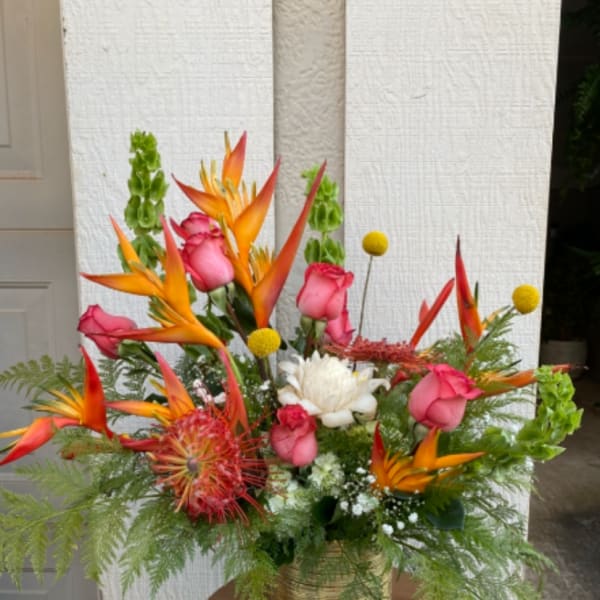 Tropical bouquet with pink roses and orange bird-of-paradise in a gold vase