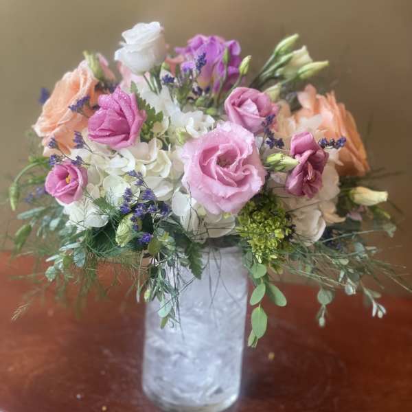 Pink and white flowers arranged in a clear glass vase