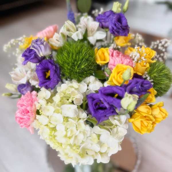Colorful bouquet with purple, yellow, pink, and white flowers in a glass vase