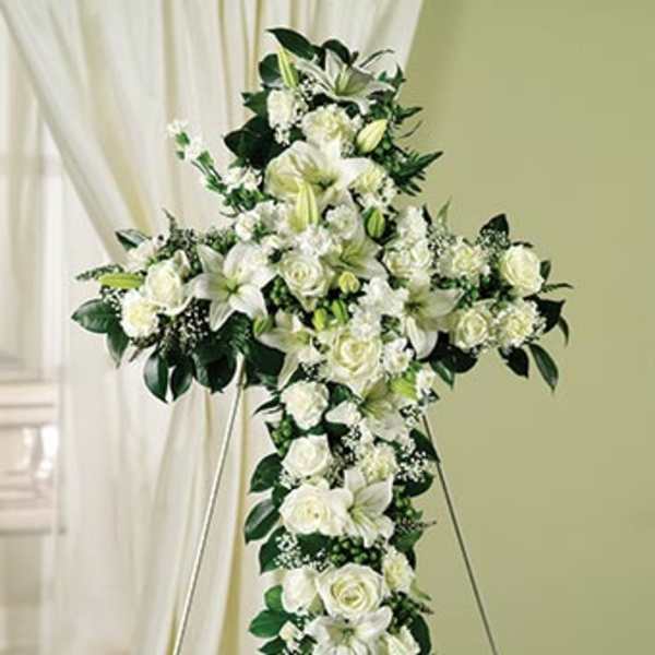White floral cross arrangement on a stand