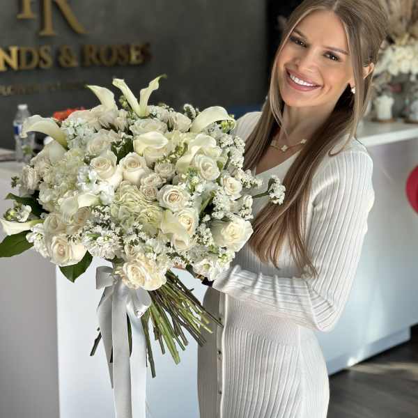 Woman holding a large white bouquet with roses and calla lilies